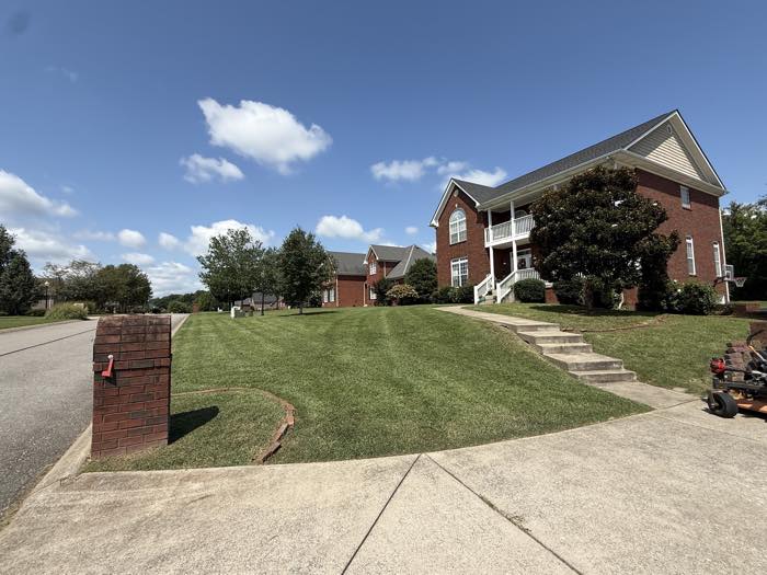 Fresh mowing stripes across a sloped brick-home front lawn