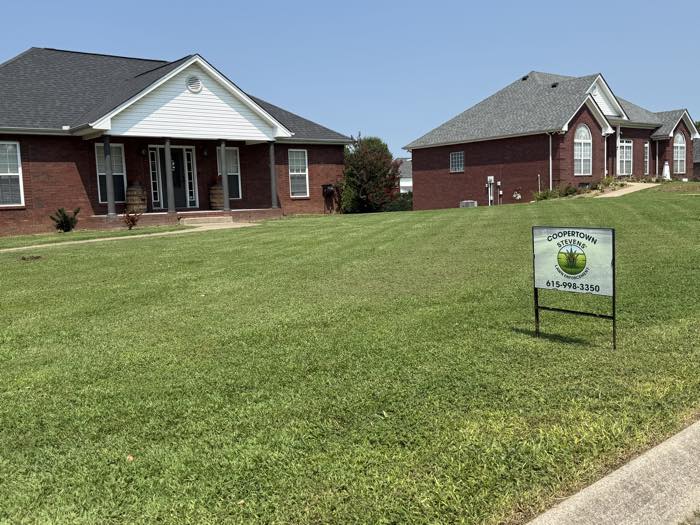 Stevens' Lawn Enforcement yard sign staked in a freshly cut Coopertown lawn